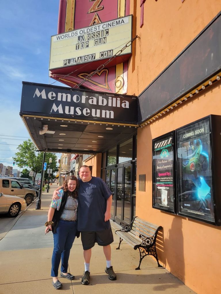 Man and woman smiling for a photo in front of a movie theater